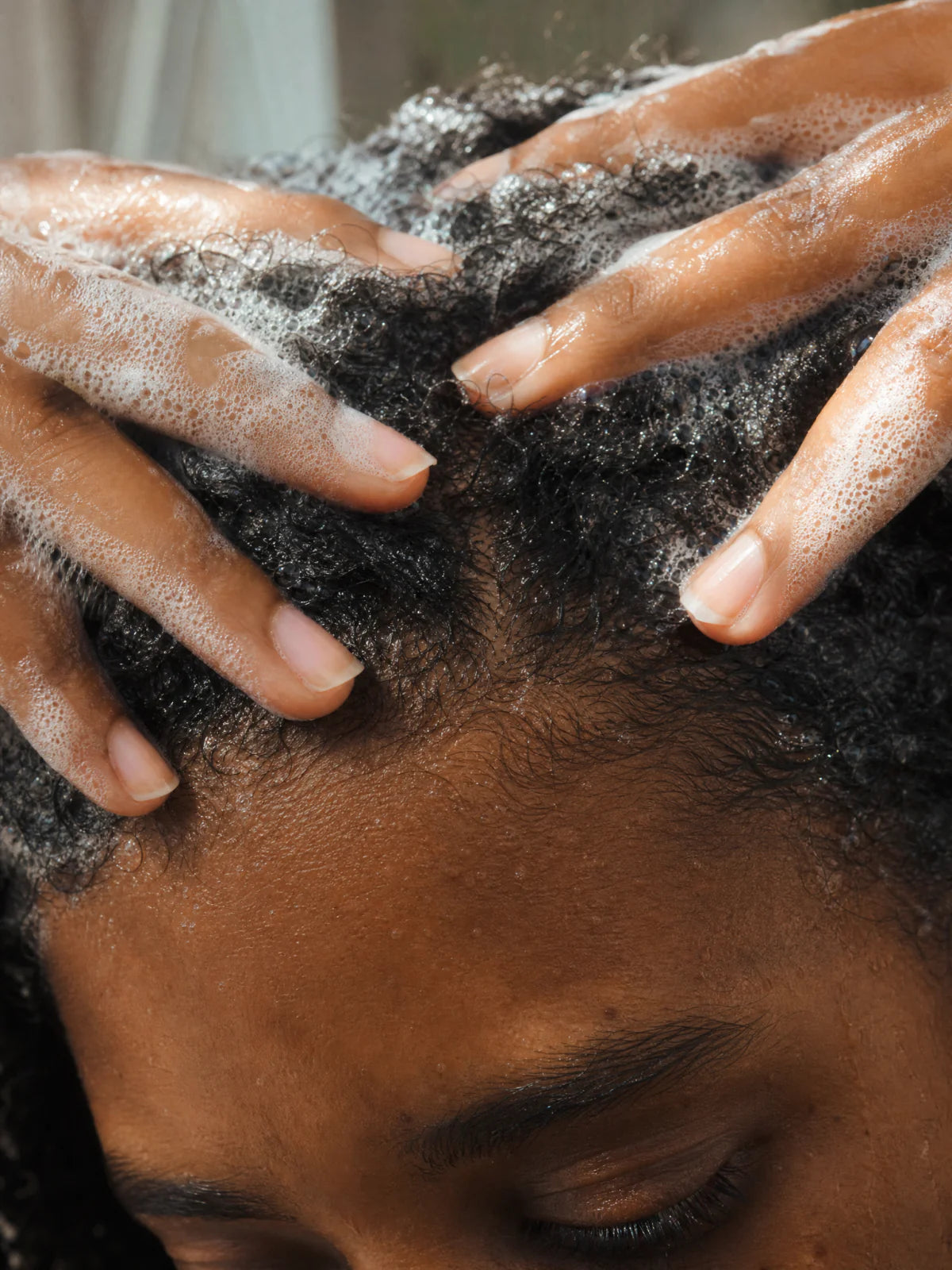 Cuir chevelu purifié - mains massant mousse claire sur cheveux crépus